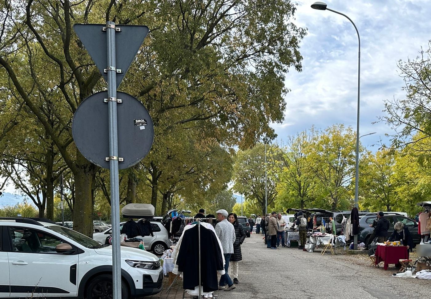 La fila dei bagagliai aperti lungo il viale, con i visitatori che curiosano