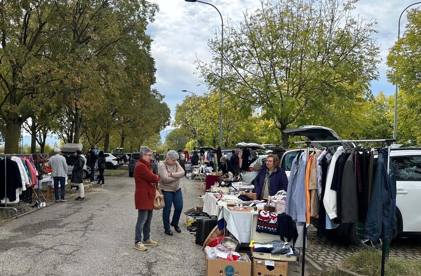 Due visitatrici si fermano davanti a un banco di vestiti e oggetti