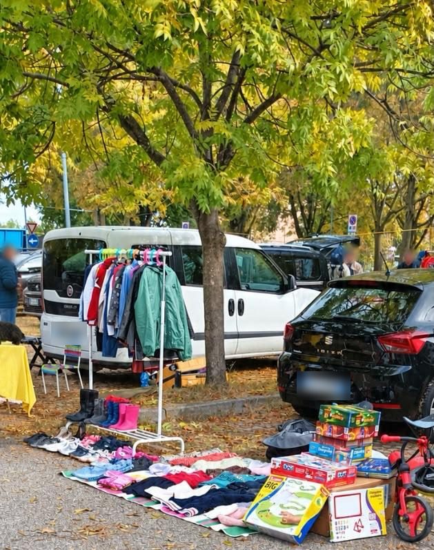 Un telo pieno di vestiti, scarpe e giochi per bambini, con uno stendino di giacchine colorate